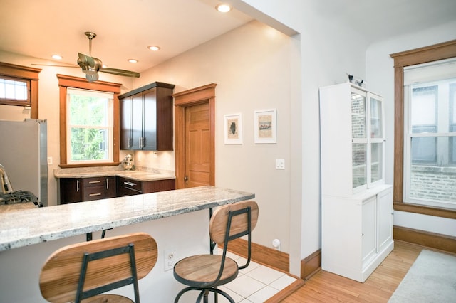 5338 S Greenwood Ave Unit 3, Chicago, IL 60615 - kitchen with freestanding refrigerator, a breakfast bar area, light wood-style flooring, light stone countertops, and dark brown cabinetry