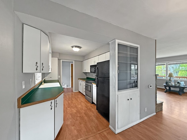 1612 Parkside Ct, Freeport, IL 61032 - kitchen with black appliances, light wood-style floors, a sink, white cabinetry, and baseboards