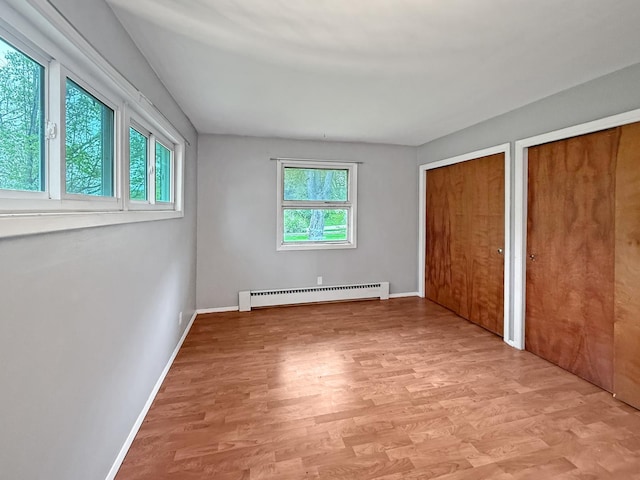 1612 Parkside Ct, Freeport, IL 61032 - unfurnished bedroom featuring a baseboard heating unit, two closets, light wood-style flooring, and baseboards