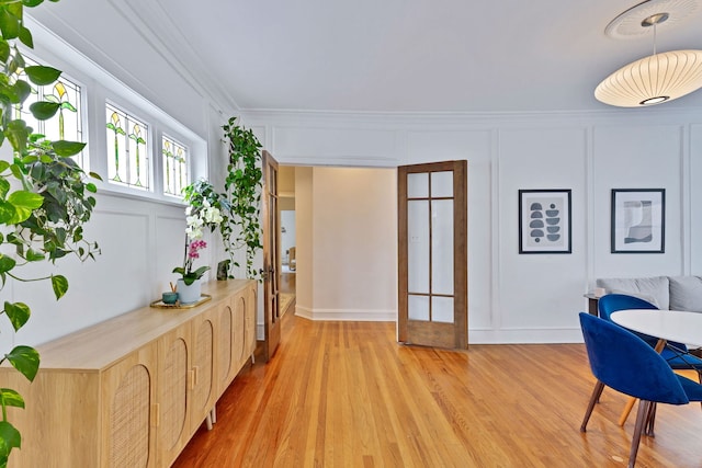 dining area featuring a decorative wall, light wood-style flooring, and crown molding