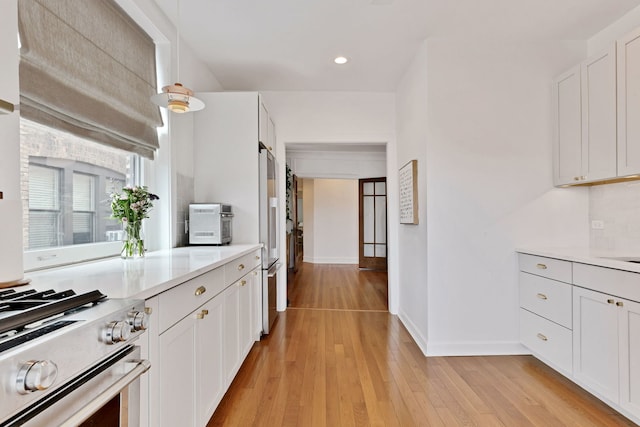 kitchen with appliances with stainless steel finishes, recessed lighting, baseboards, light countertops, and light wood finished floors