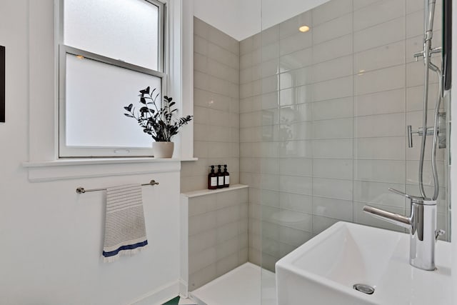 full bathroom with tiled shower and a sink