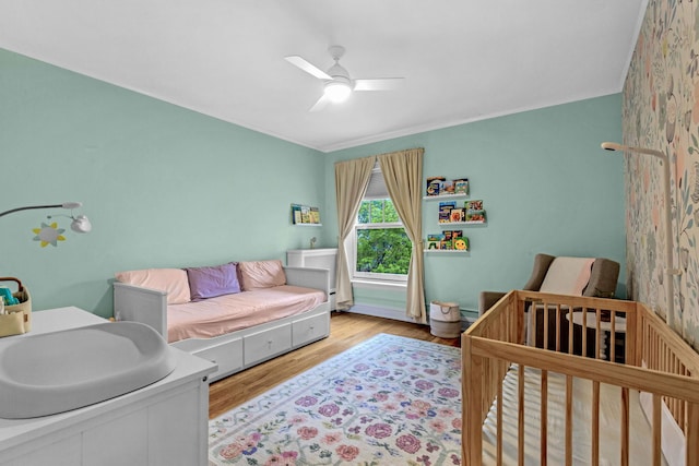 bedroom with wood finished floors, ceiling fan, and ornamental molding