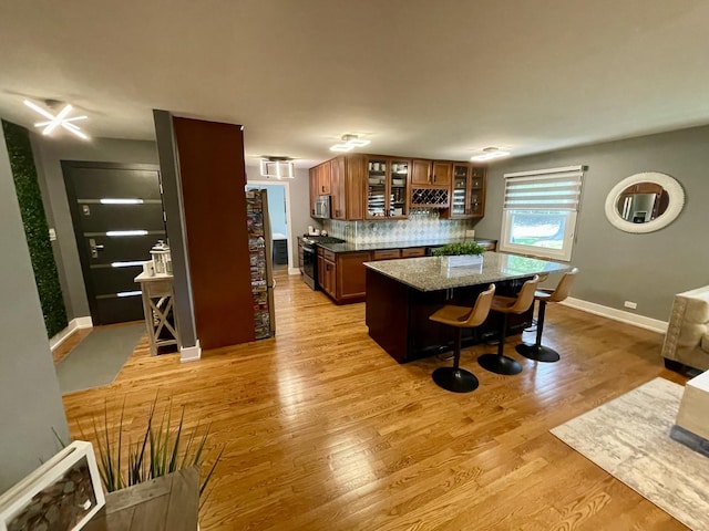 443 Indianwood Dr, Carol Stream, IL 60188 - kitchen featuring stainless steel appliances, brown cabinetry, glass insert cabinets, backsplash, and a kitchen island