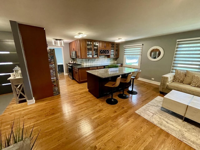 443 Indianwood Dr, Carol Stream, IL 60188 - kitchen with appliances with stainless steel finishes, a kitchen bar, brown cabinetry, glass insert cabinets, and light wood-type flooring