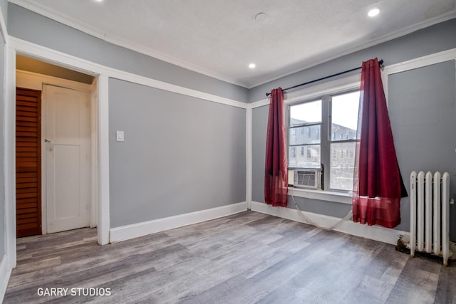 spare room featuring radiator heating unit, ornamental molding, wood finished floors, recessed lighting, and baseboards