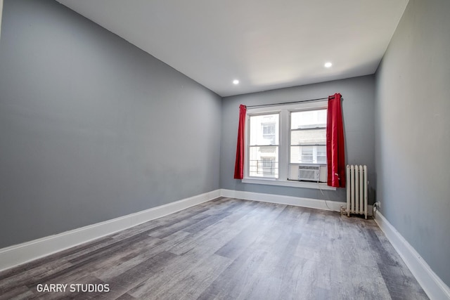 spare room featuring radiator heating unit, wood finished floors, baseboards, and recessed lighting