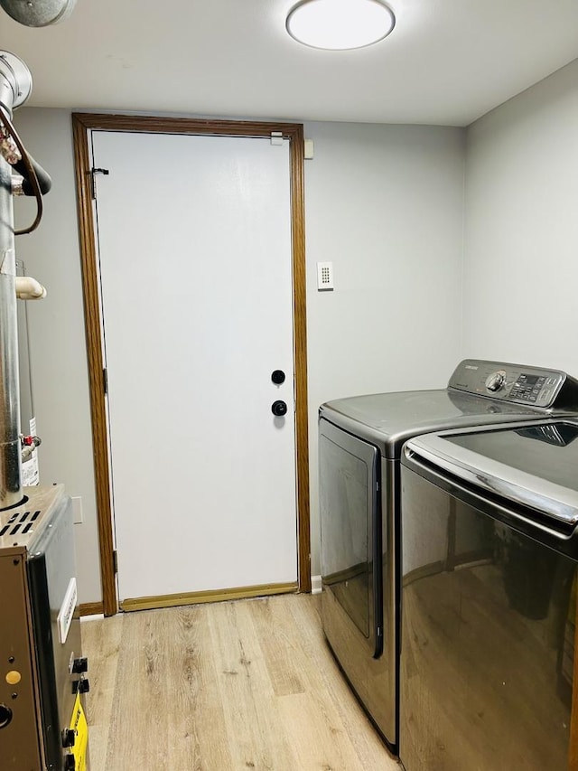 laundry area featuring baseboards, washing machine and dryer, laundry area, and light wood-style flooring