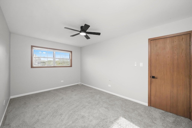 carpeted empty room featuring baseboards and a ceiling fan