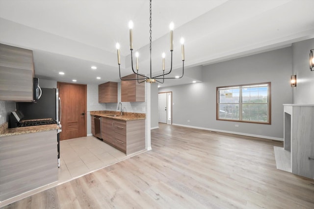 kitchen with modern cabinets, a chandelier, stainless steel appliances, brown cabinets, and tasteful backsplash