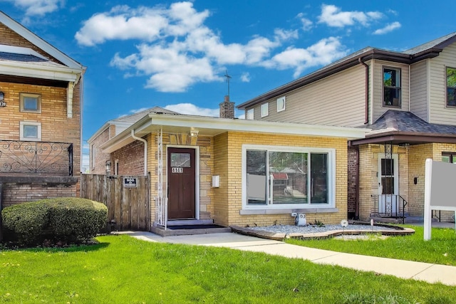 view of front facade featuring a front yard, brick siding, and fence