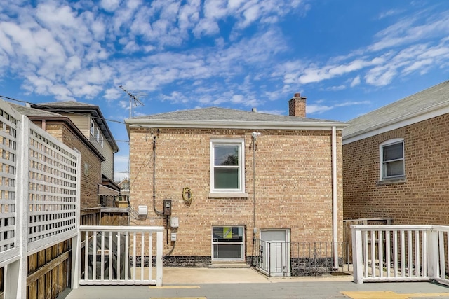 back of house with fence, a chimney, and brick siding