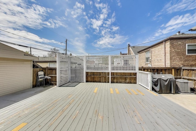 deck with cooling unit, area for grilling, and a fenced backyard