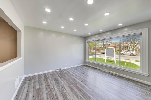 unfurnished room with baseboards, recessed lighting, visible vents, and wood finished floors