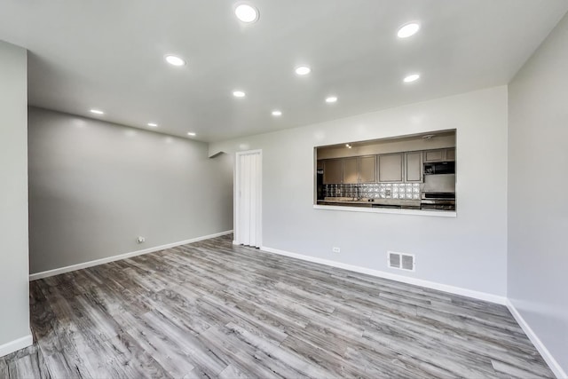 unfurnished living room with visible vents, wood finished floors, baseboards, and recessed lighting