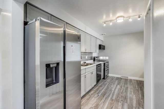 kitchen featuring stainless steel appliances, light wood-type flooring, visible vents, backsplash, and light countertops