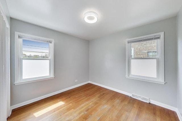 spare room with baseboards, visible vents, and light wood-style floors