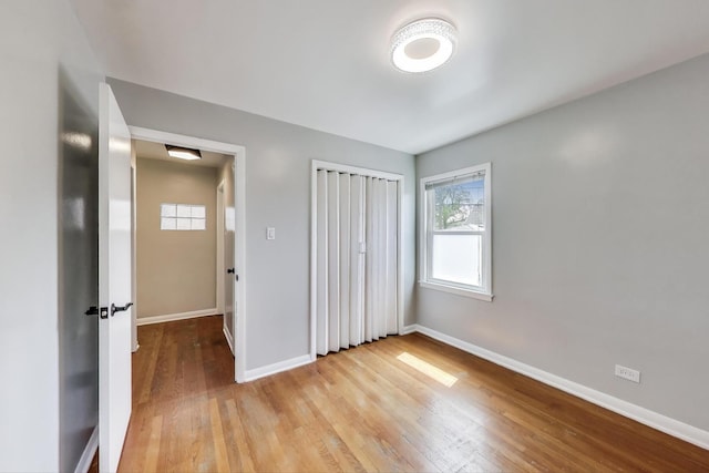 unfurnished bedroom featuring baseboards, light wood-style floors, and a closet