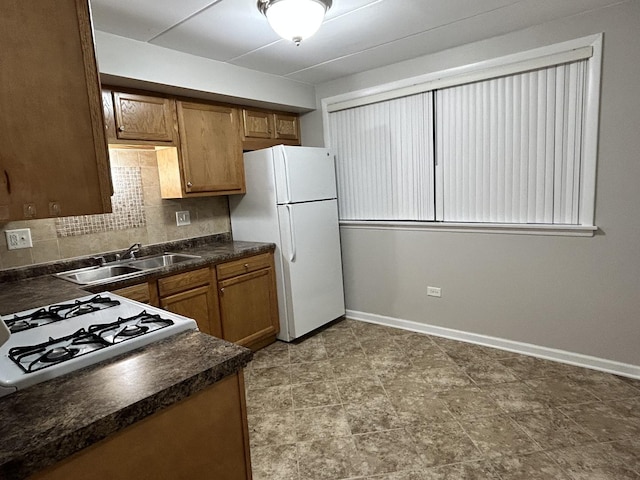 kitchen featuring a sink, freestanding refrigerator, and dark countertops