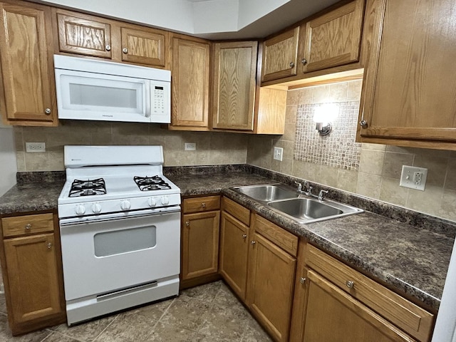 kitchen with brown cabinets, white appliances, decorative backsplash, and a sink