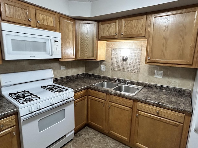 kitchen with a sink, white appliances, and dark countertops