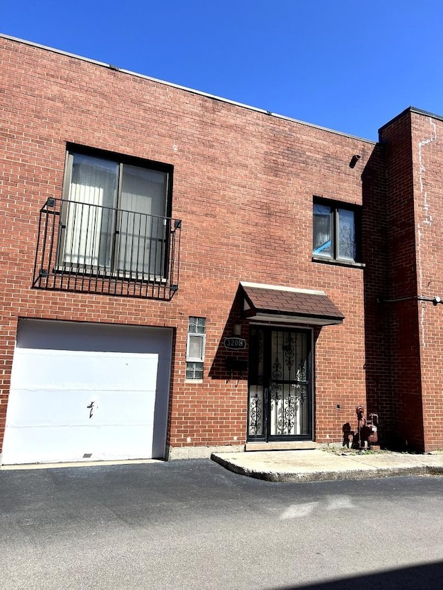 view of front of house with brick siding, an attached garage, and asphalt driveway