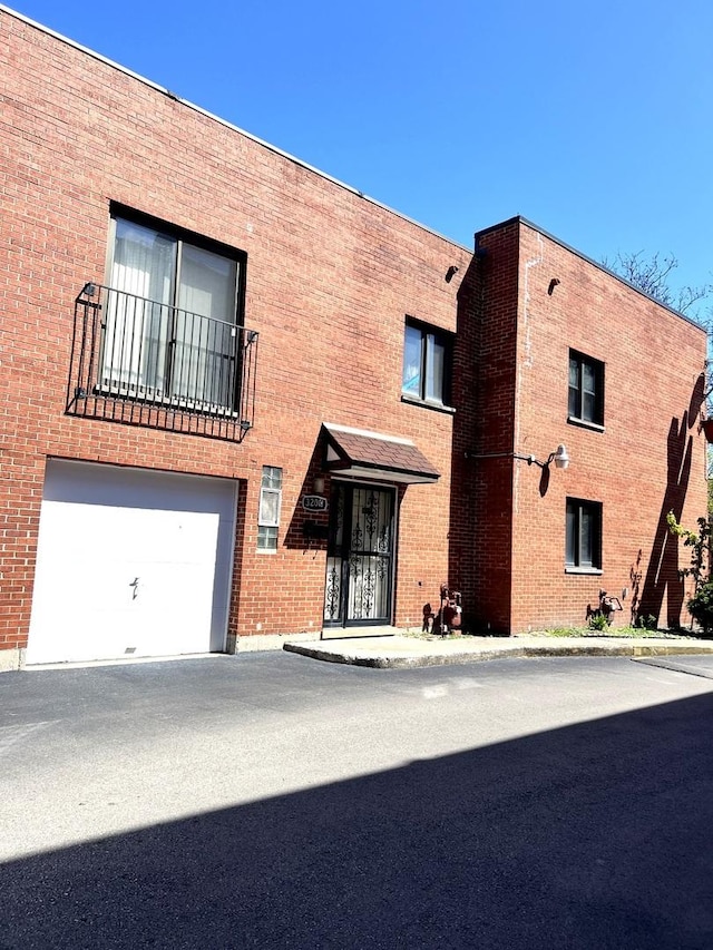view of front of house featuring brick siding, a balcony, and an attached garage