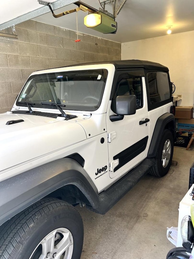 garage featuring a garage door opener and concrete block wall