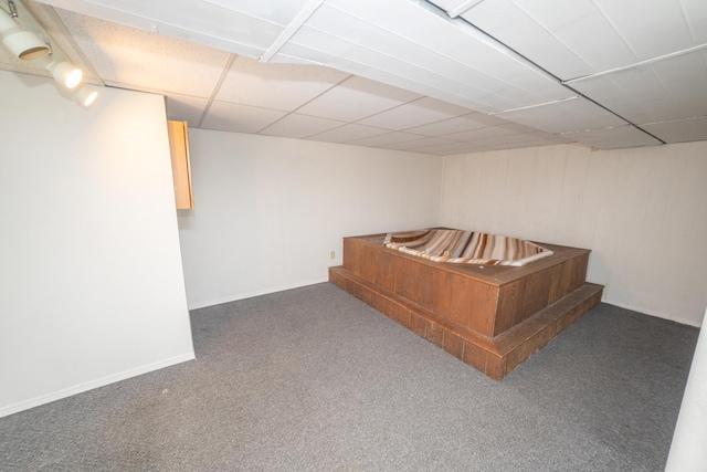 finished below grade area featuring carpet, a paneled ceiling, and baseboards