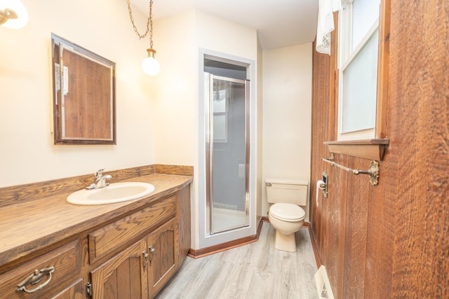 bathroom featuring wood finished floors, toilet, a shower stall, and vanity