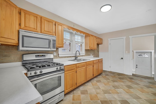 kitchen with light countertops, appliances with stainless steel finishes, tasteful backsplash, and a sink