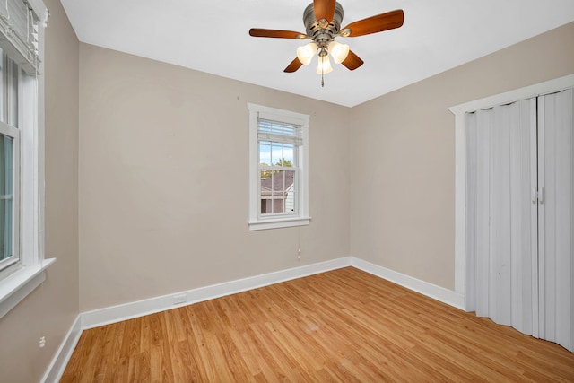 unfurnished bedroom featuring baseboards, a closet, a ceiling fan, and light wood-style floors