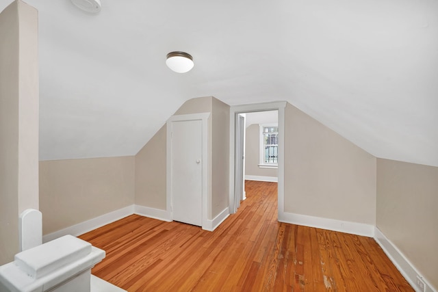 bonus room featuring lofted ceiling, light wood-style flooring, and baseboards