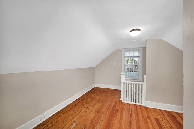 additional living space featuring wood finished floors, vaulted ceiling, and baseboards