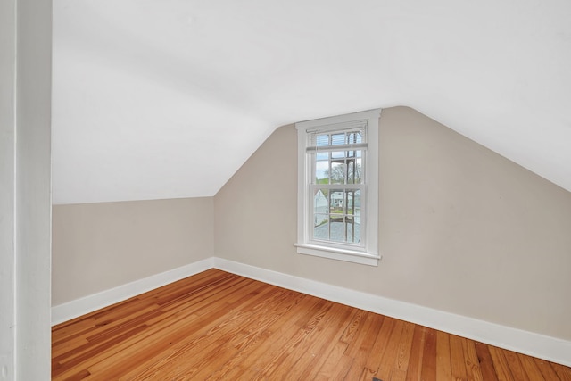 additional living space with wood finished floors, vaulted ceiling, and baseboards