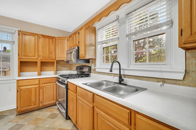 kitchen featuring light countertops, appliances with stainless steel finishes, a sink, and plenty of natural light
