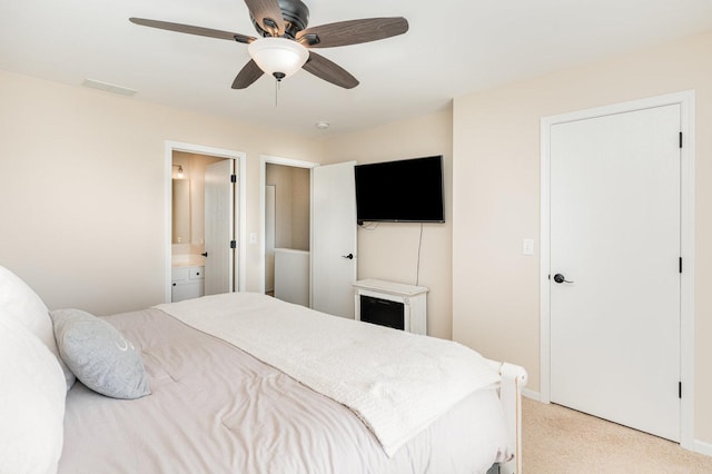 bedroom with light carpet, baseboards, ensuite bathroom, and ceiling fan