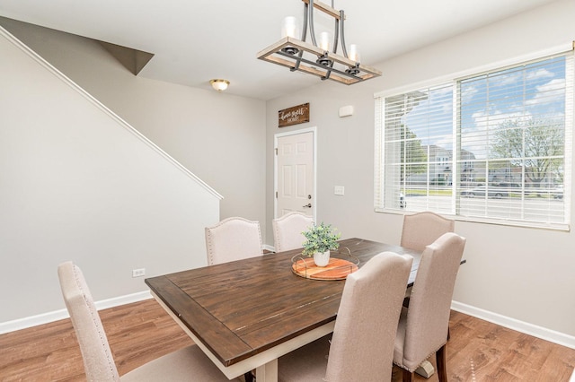 dining space featuring a chandelier, light wood-type flooring, and baseboards
