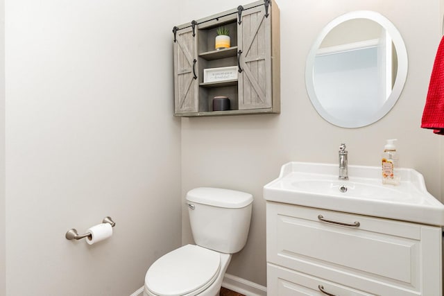 bathroom with toilet, vanity, and baseboards