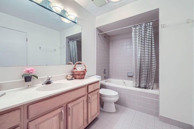 bathroom featuring tile patterned flooring, tiled shower / bath, vanity, and toilet