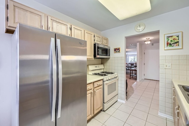 kitchen featuring stainless steel appliances, light tile patterned floors, tile walls, light countertops, and light brown cabinets