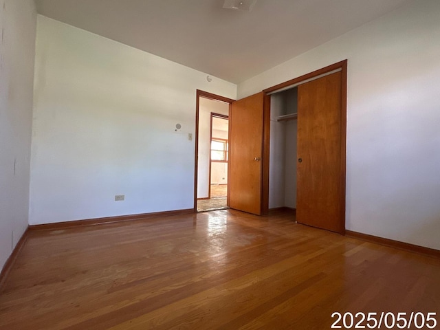 unfurnished bedroom featuring baseboards, a closet, and wood finished floors