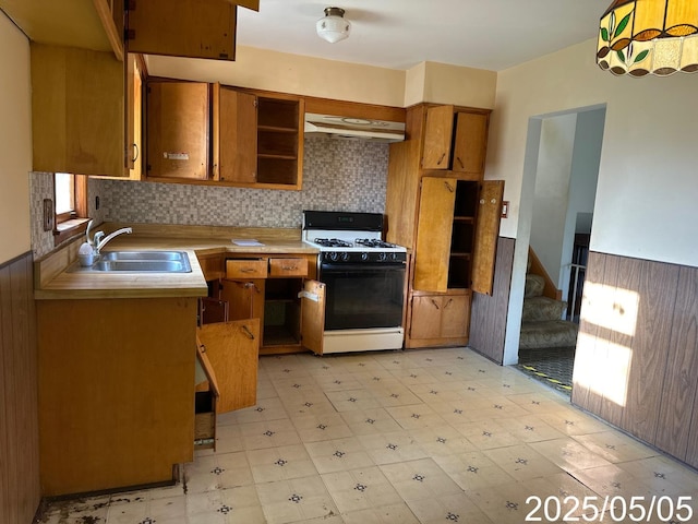 kitchen with a sink, range with gas cooktop, under cabinet range hood, and brown cabinets