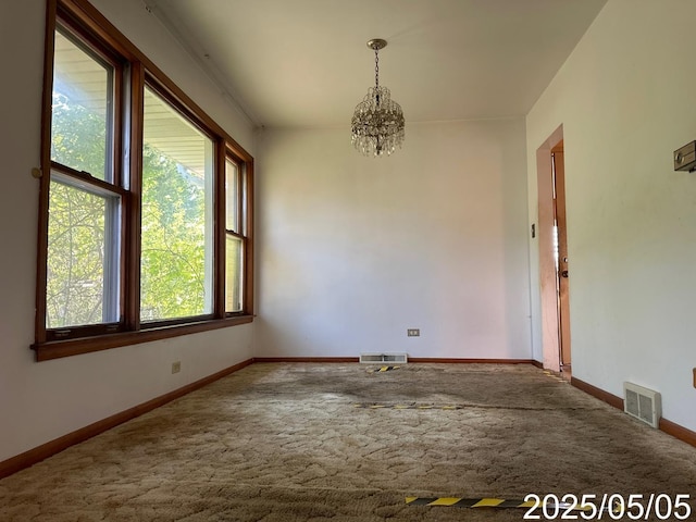 carpeted spare room with a notable chandelier, baseboards, and visible vents