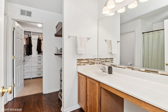 bathroom with wood finished floors, vanity, tasteful backsplash, and baseboards