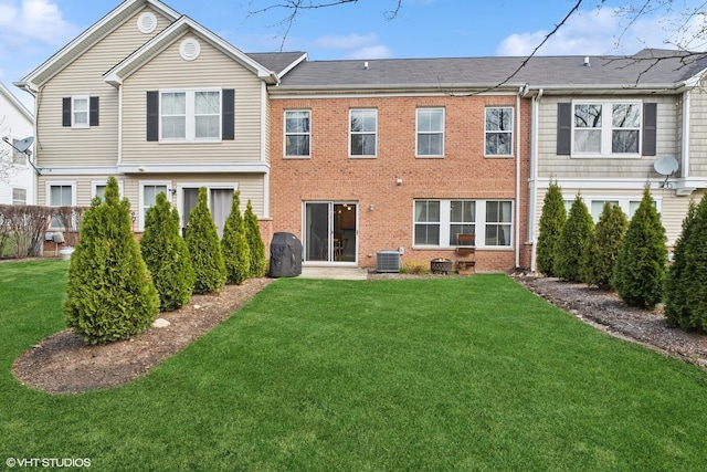 back of property featuring a yard, brick siding, and cooling unit
