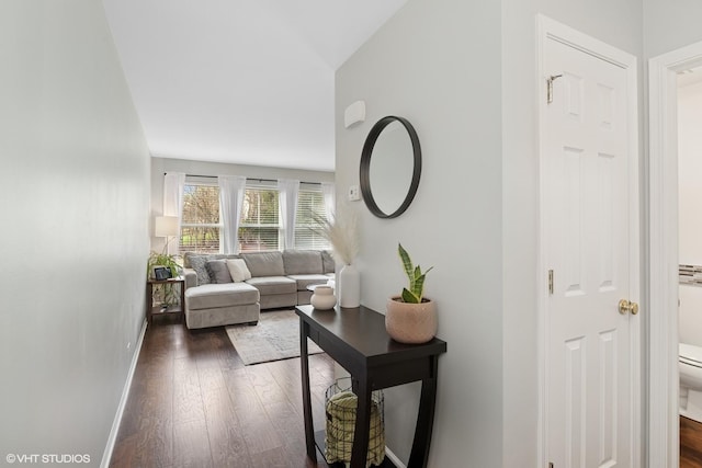 living room featuring dark wood-type flooring, baseboards, and lofted ceiling