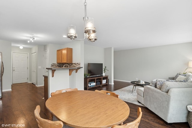 dining room with dark wood-style floors, a chandelier, and baseboards
