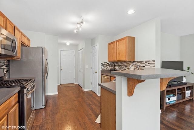 kitchen with stainless steel appliances, a kitchen bar, a peninsula, backsplash, and recessed lighting