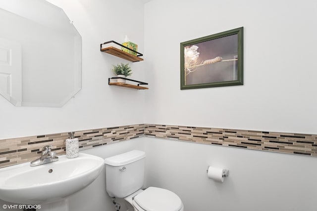 bathroom featuring a sink, toilet, and tasteful backsplash